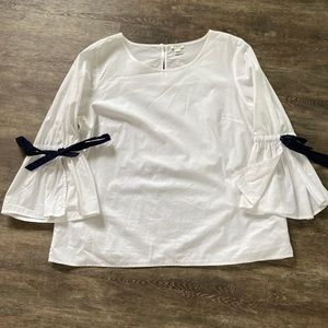 White shirt with long split, tied sleeves.